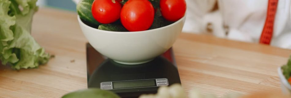 Colorful fresh vegetables including tomatoes and cucumbers on a kitchen scale for healthy eating.